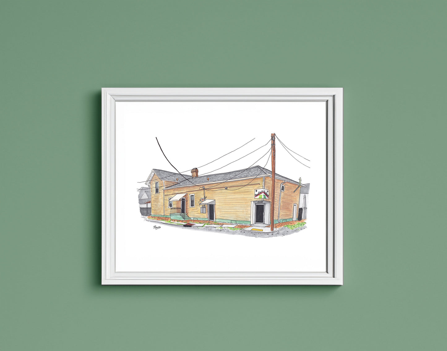A detail photo of the Domilise's PoBoy art print in a frame.The finished piece sits in a white frame on a warm green wall. The frame matches the white background on which the restaurant floats in the artwork.