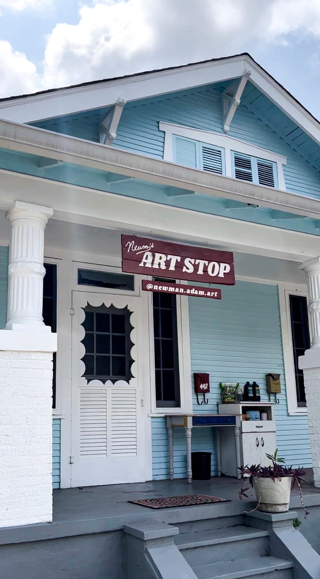 Blue house at 442 Belleville Street, New Orleans with a sign reading 'Newm's Art Stop' on a cloudy day.