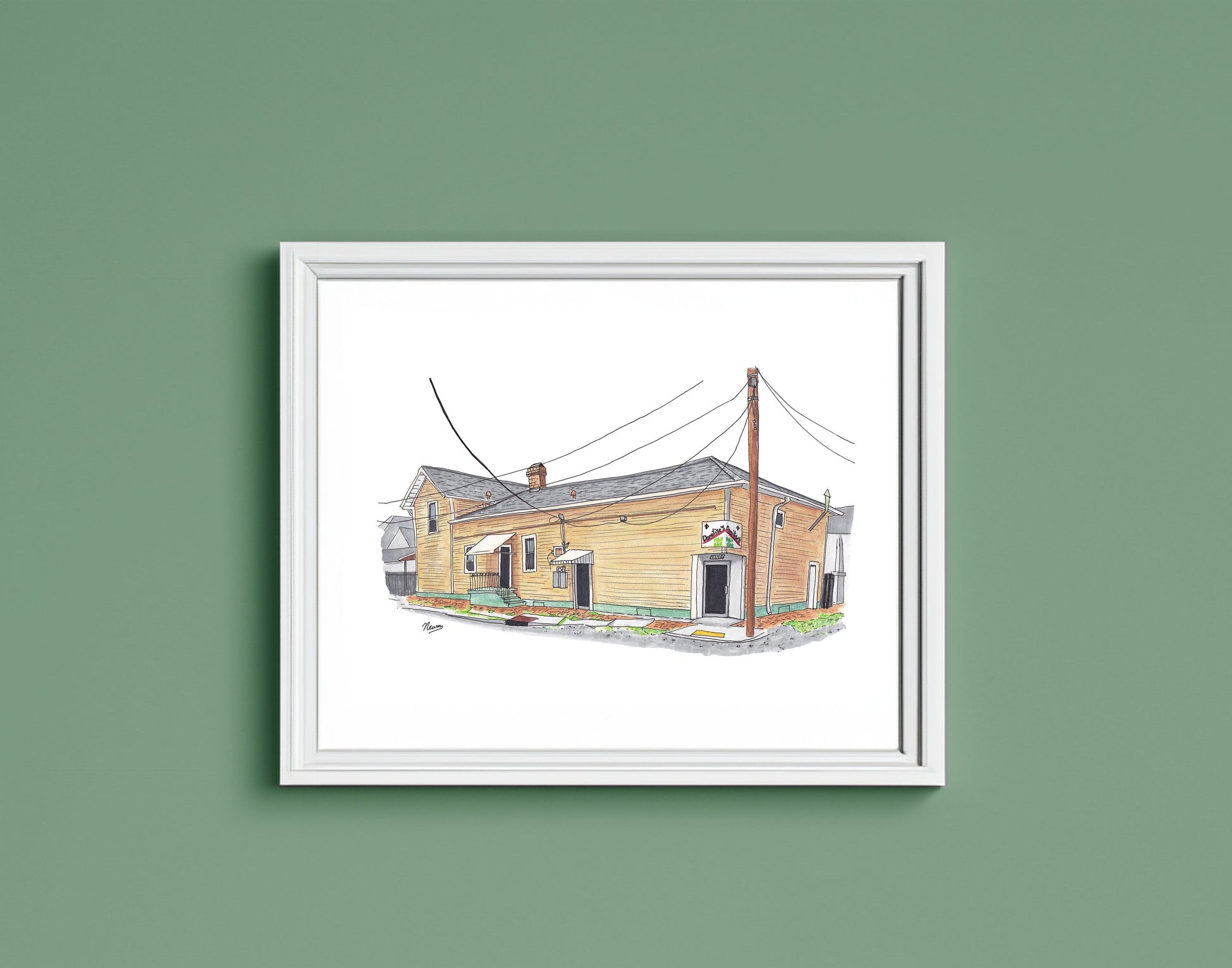A detail photo of the Domilise's PoBoy art print in a frame.The finished piece sits in a white frame on a warm green wall. The frame matches the white background on which the restaurant floats in the artwork.